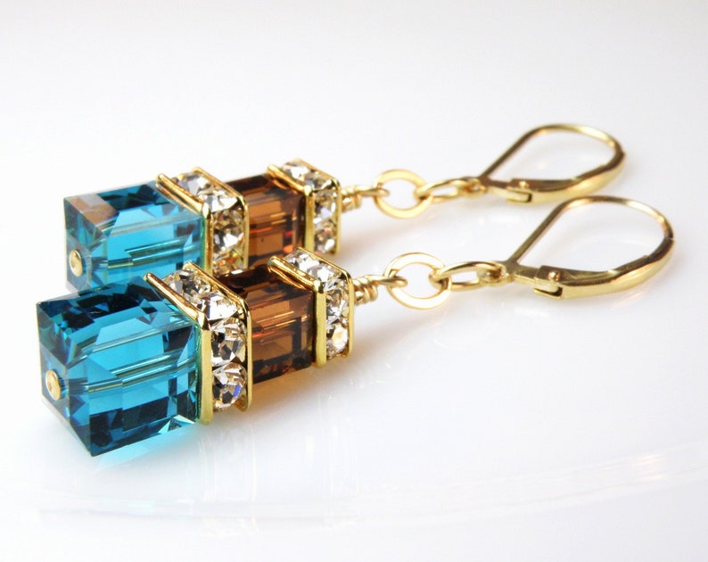 crystal dangle earrings with small chocolate brown cube on top of a larger deep teal blue cube with rhinestone crowns on top and set on gold leverbacks