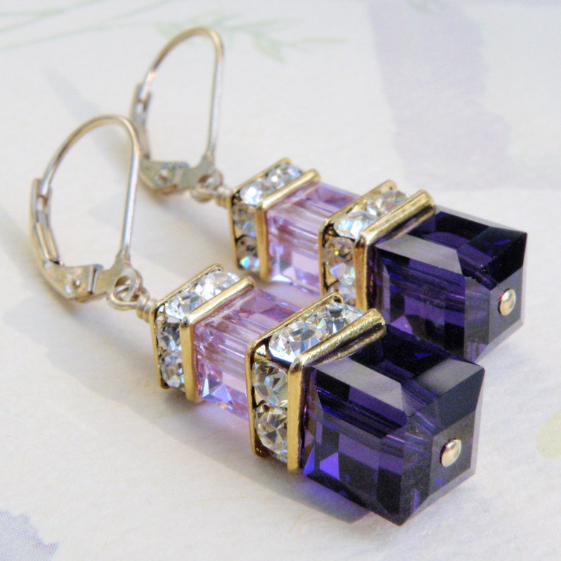 crystal dangle earrings with small light violet cube on top of a larger dark purple cube with rhinestone crowns on top and set on gold leverbacks