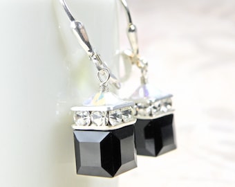 May include: A pair of silver dangle earrings with black square-shaped crystal drops and clear crystal accents.