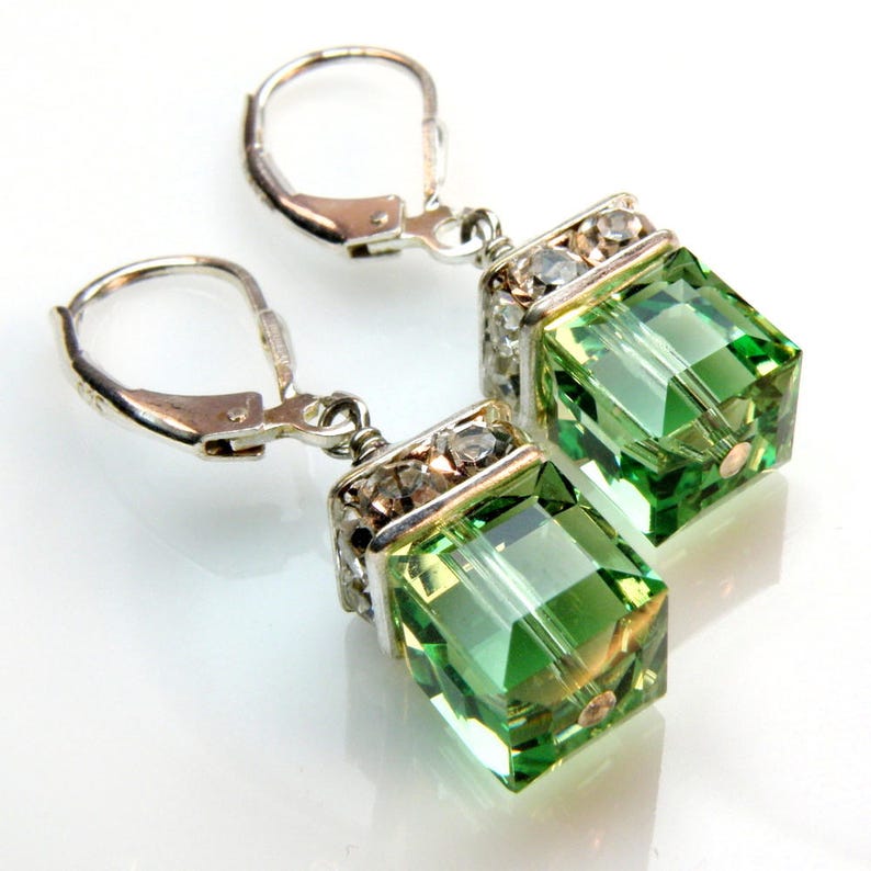 crystal cube dangle earrings in light peridot green color with silver rhinestone crowns on top and set on silver leverback earring closures