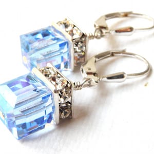 crystal cube dangle earrings in light sapphire blue color with silver rhinestone crowns on top and set on silver leverback earring closures