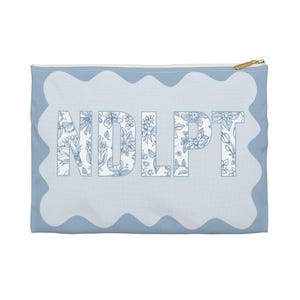 May include: A light blue zippered pouch with a white scalloped border. The pouch has a floral design with the letters "NDLPT" in the center.