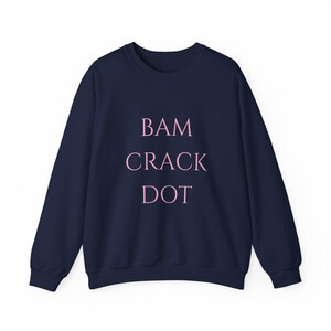 May include: Navy blue sweatshirt with the words "BAM CRACK DOT" printed in pink.