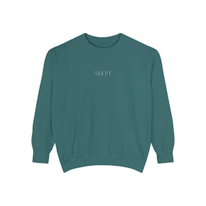 May include: Teal-colored sweatshirt with long sleeves. The word "NDLPT" is printed in a small, light font across the chest. The sweatshirt is made of a soft material and has a crew neck.