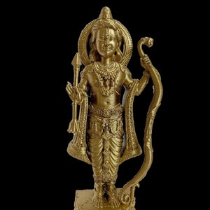 May include: A gold-colored statue of a Hindu deity, possibly Rama, standing on a decorative base. The statue is holding a bow and arrow in one hand and a spear in the other.