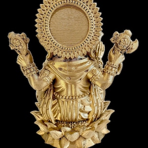 May include: A gold-colored statue of the Hindu goddess Lakshmi, sitting on a lotus flower. She is holding a pot of gold in one hand and a lotus flower in the other. She is wearing a crown and jewelry. The statue is a traditional Indian religious icon.