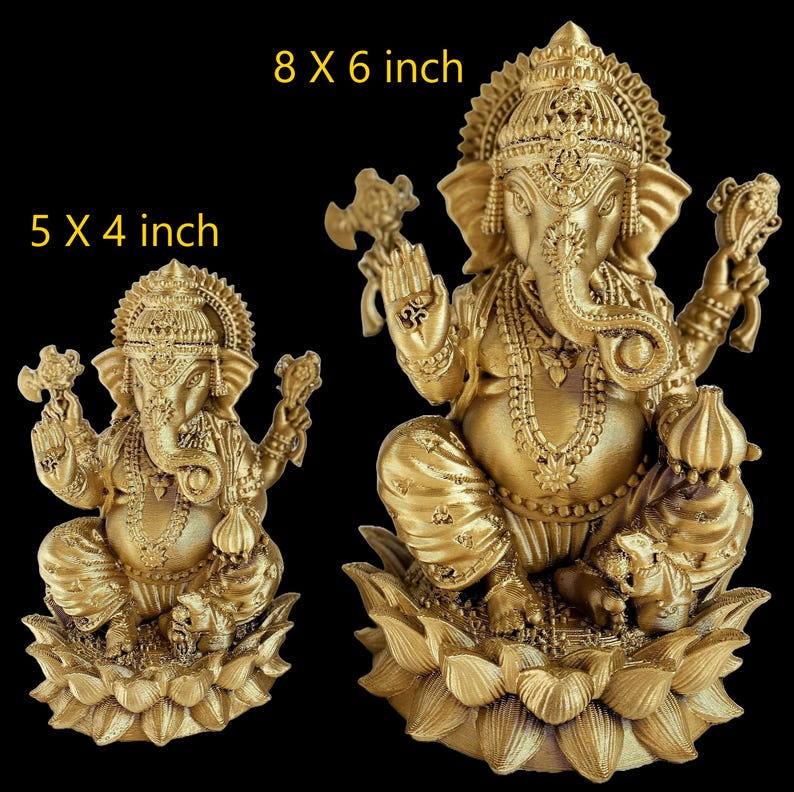 May include: Two gold-colored Ganesha statues, one is 5 x 4 inches and the other is 8 x 6 inches. Both statues are sitting on lotus flower bases.