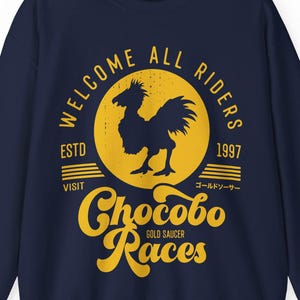 Puede incluir: Sudadera azul marino con un gráfico amarillo que representa un pájaro estilizado dentro de un círculo, con el texto "WELCOME ALL RIDERS", "ESTD 1997" y "Chocobo Races". La sudadera tiene mangas largas y cuello redondo.