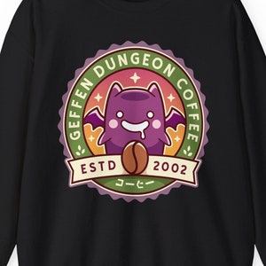 May include: Black sweatshirt with a green, white, and orange circular logo featuring a purple bat with a coffee bean in its mouth. The logo reads "Geffen Dungeon Coffee" and "Est. 2002".