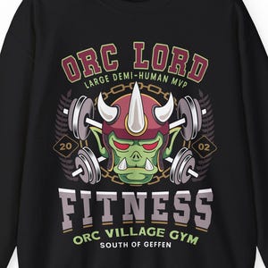 May include: Black sweatshirt with a graphic featuring an orc with a red horned helmet lifting weights. The text reads "Orc Lord Fitness Orc Village Gym South of Geffen". The design includes barbells and the numbers "20" and "02".
