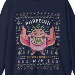 May include: Navy blue sweatshirt featuring a colorful graphic of a monster with the text "PHREONI" above it. Below the monster is the text "SOGRAT DESERT MVP". The design includes Christmas tree and ornament motifs.