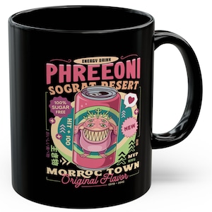 May include: Black ceramic mug featuring a colorful graphic design. The design includes the text "PHREEONI SOGRAT DESERT" with a cartoon can and monster. The mug also has the text "MORROC TOWN Original Flavor".