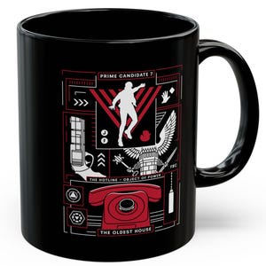 May include: A black ceramic mug featuring a graphic design in red and white. The print includes a silhouette of a person, a red rotary telephone, and text reading PRIME CANDIDATE 7, THE HOTLINE - OBJECT OF POWER, and THE OLDEST HOUSE with various symbols.