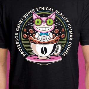 Op de afbeelding: Zwart t-shirt met een cartoonkat in een koffiekopje. Het ontwerp bevat de tekst "Professor Genki Super Ethical Reality Climax Coffee". De kat draagt een bril en een vlinderdas. Koffiebonen omringen de kop, die op een roze schotel staat.