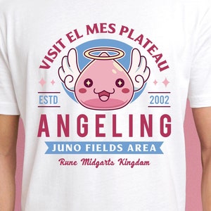 May include: White t-shirt with a pink and blue graphic design featuring a cartoon angel with a halo and wings. The text reads "Visit El Mes Plateau Estd 2002 Angelina Juno Fields Area Rune Midgarts Kingdom".