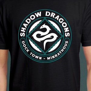 Puede incluir: Camiseta negra con un gráfico circular blanco que presenta un diseño de dragón turquesa y el texto "Shadow Dragons Dock Town - Minrathous".