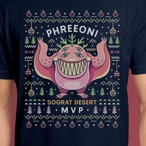 May include: Navy blue t-shirt featuring a pink monster graphic with the text "PHREEONI" above and "SOGRAT DESERT MVP" below. The design includes Christmas-themed elements like trees and ornaments.
