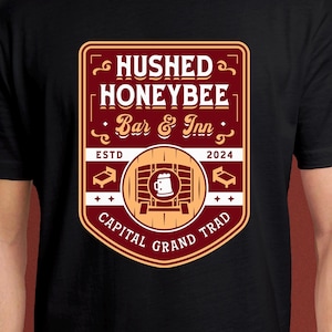 May include: Black t-shirt with a red and gold logo that says "Hushed Honeybee Bar & Inn" with the text "ESTD 2024 Capital Grand Trad" underneath.