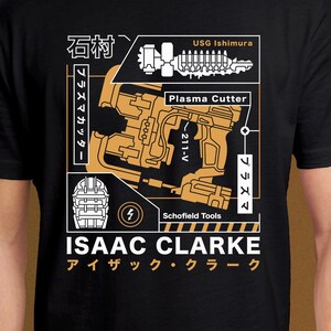 May include: Black t-shirt featuring a gold and white graphic design. The design includes the text "Plasma Cutter", "ISAAC CLARKE", and Japanese characters. The shirt also features a schematic-like illustration of a weapon.