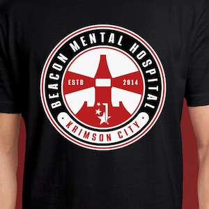 Könnte beinhalten: Schwarzes T-Shirt mit einem kreisförmigen Design. Der Aufdruck zeigt "BEACON MENTAL HOSPITAL" und "KRIMSON CITY". Das Design hat eine rot-weiße Grafik, das Jahr "2014" und das Wort "ESTD".