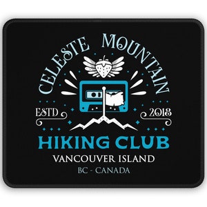 May include: Black mousepad with a white logo for the Celeste Mountain Hiking Club. The logo features a cassette tape, a strawberry with wings, and the text "Celeste Mountain Hiking Club, Vancouver Island, BC - Canada, Est. 2018."