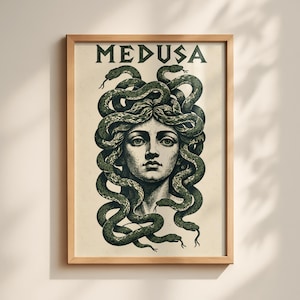 May include: A framed wall art print featuring a central illustration of Medusa with dark green snakes for hair. The word MEDUSA is printed in bold black capital letters at the top. The artwork is set against a cream-colored background.