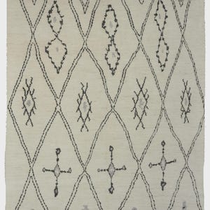 May include: A rectangular area rug featuring an off-white base color with a repeating dark gray diamond grid pattern. Inside each diamond shape are smaller, distinct gray and dark gray geometric symbols. The rug has short fringe at both ends.