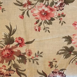 May include: Close-up of a floral fabric featuring a repeating pattern of large, pink and red flowers with green and brown leaves on a beige background. The fabric has a linen-like texture.