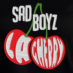 May include: Black t-shirt with an embroidered design of two red cherries with white lettering, featuring the text "SAD BOYZ LA CHERRY".