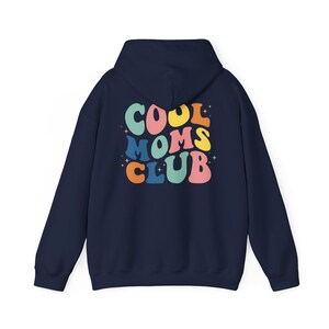 May include: Navy blue hooded sweatshirt with the text "COOL MOMS CLUB" in rainbow colors on the back.