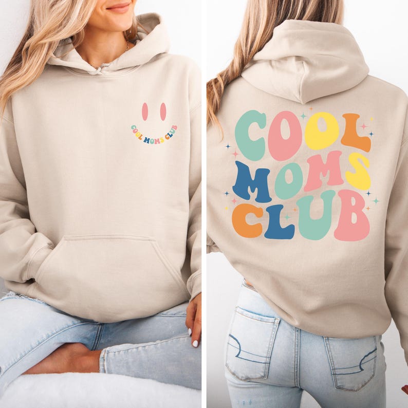 May include: A beige hoodie with a smiling face and the text "Cool Moms Club" on the front. The back of the hoodie has the text "COOL MOMS CLUB" in colorful, retro-style letters.