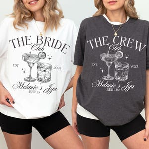 Könnte beinhalten: Zwei weiße T-Shirts mit schwarzem Text und Grafiken. Der Text auf dem linken Shirt lautet "The Bride Club Est. 2025 Melanie's Iga Berlin". Der Text auf dem rechten Shirt lautet "The Crew Club Est. 2025 Melanie's Iga Berlin".