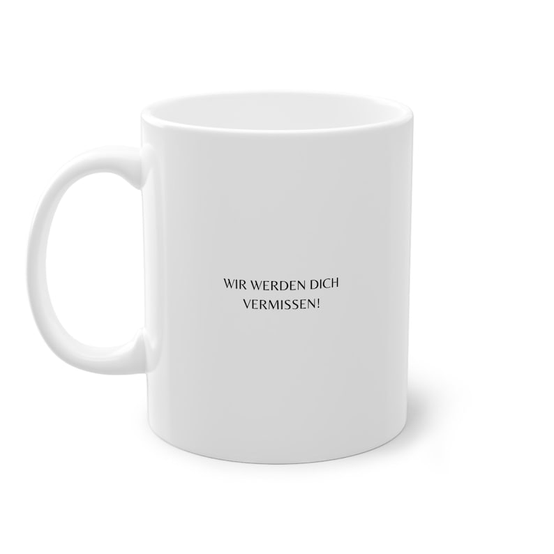 May include: White ceramic coffee mug with black text that reads "Wir werden dich vermissen!" which translates to "We will miss you!" in English.