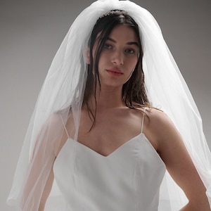 Op de afbeelding: Een witte bruidsjurk met een sweetheart-halslijn en een sluier. De jurk heeft een getailleerd lijfje en een zwierige rok.