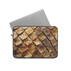 Pode incluir: Uma capa para laptop com um padrão de escamas marrons e douradas. As escamas são dispostas em um padrão repetitivo e têm uma aparência texturizada.