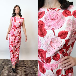 Puede incluir: Vestido largo sin mangas con estampado floral en tonos rosas y rojos. El vestido presenta un corpiño ajustado y una falda recta. La tela está adornada con abalorios, añadiendo textura y detalle al diseño.