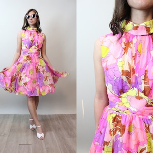 May include: A pink, yellow, and purple floral print dress with a high neck and sleeveless design. The dress has a fitted bodice and a flared skirt.