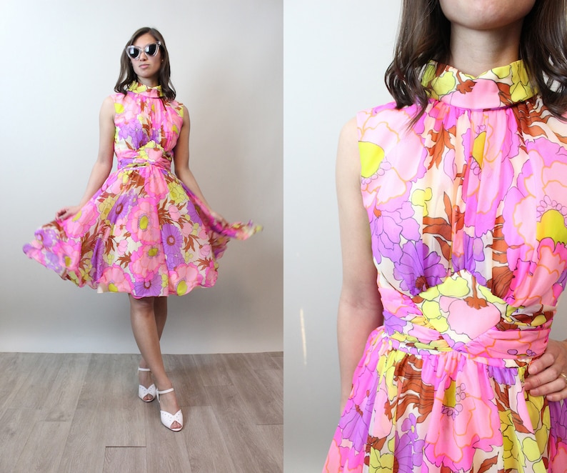 May include: A pink, yellow, and purple floral print dress with a high neck and sleeveless design. The dress has a fitted bodice and a flared skirt.
