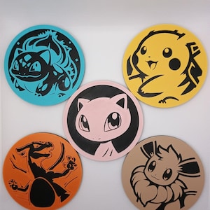 May include: Five circular coasters featuring stylized black graphic illustrations of various creatures. The coasters are colored in light blue, yellow, light pink, orange, and tan, each displaying a distinct character design on a flat surface.