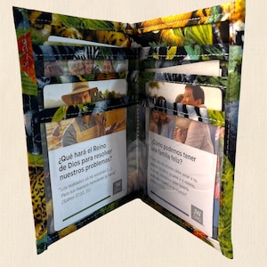 May include: Open wallet with a colorful jungle print. The wallet is open, revealing multiple card slots and inserts with printed text in Spanish. The exterior features a vibrant pattern of green, yellow, and black.