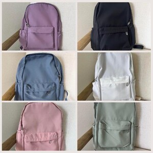 以下が含まれることがあります： 6色の異なるバックパックのセット。バックパックはすべてナイロン生地製で、前面にジッパー付きポケットが1つ付いています。色はパープル、ブラック、ホワイト、ブルー、ピンク、グリーンです。