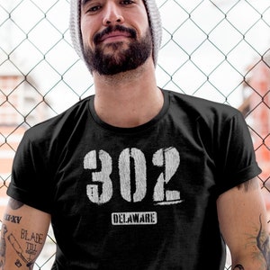 May include: A black t-shirt with a white graphic of the number 302 and the word "Delaware" underneath.