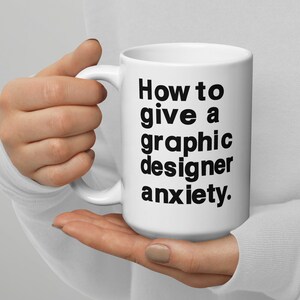 May include: White ceramic mug with black text that reads "How to give a graphic designer anxiety."