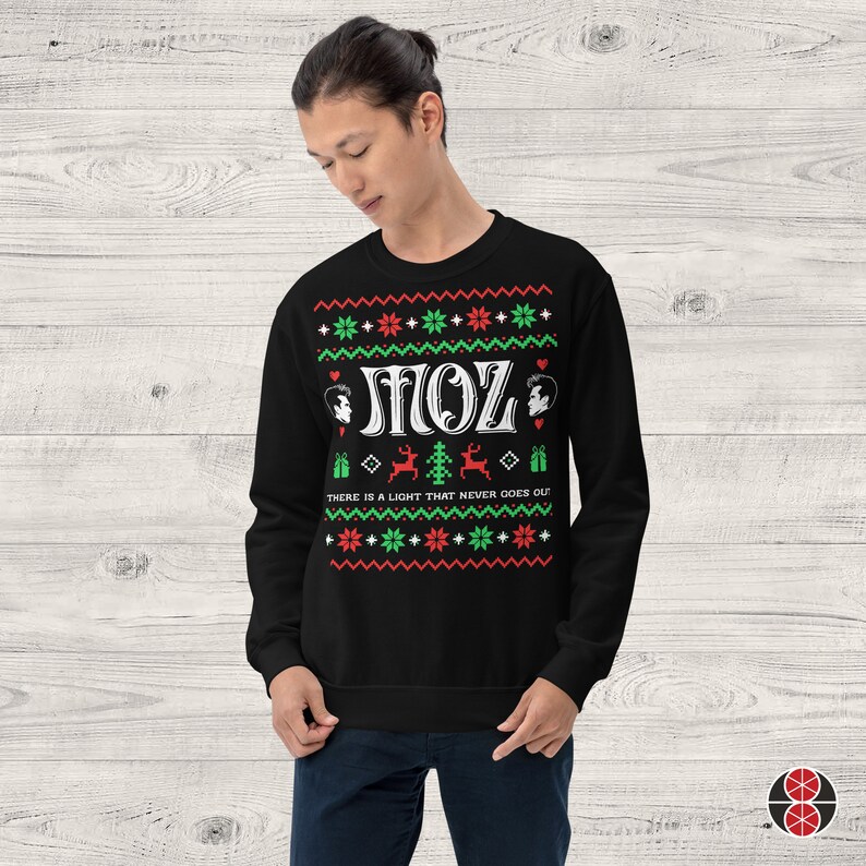 May include: Black Christmas jumper with a white "MOZ" design, two black and white portraits, and the text "THERE IS A LIGHT THAT NEVER GOES OUT!" in red and green.