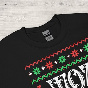 May include: Black sweatshirt with a white "HO HO HO" graphic in a festive Christmas-themed design. The graphic features red and green snowflakes and a red heart.