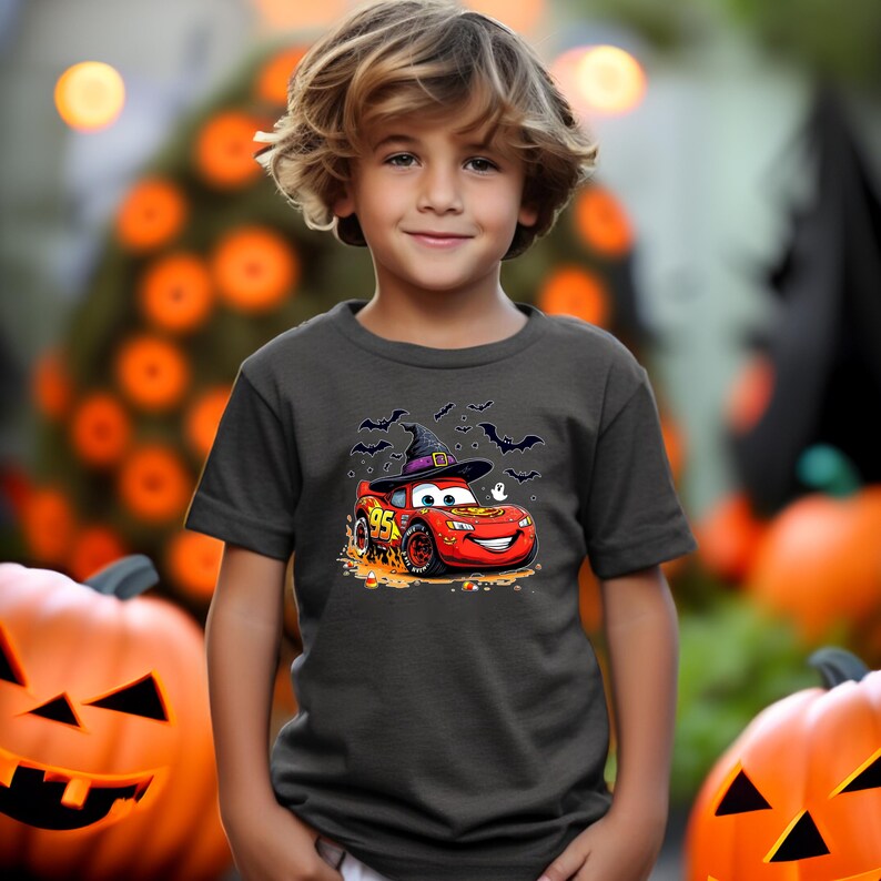 Puede incluir: Una camiseta gris oscuro de manga corta con un gr&aacute;fico de un coche de carreras rojo con el n&uacute;mero 95, que lleva un sombrero de bruja negro. El dise&ntilde;o incluye peque&ntilde;os murci&eacute;lagos negros, un fantasma blanco y caramelos naranjas en la tela.