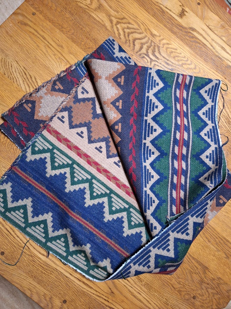 Peut inclure: Morceaux de tissu pli&eacute;s avec des motifs d'inspiration sud-ouest. Les motifs pr&eacute;sentent des formes g&eacute;om&eacute;triques dans les tons de bleu, beige, vert et rouge. Le tissu semble &ecirc;tre de poids moyen, adapt&eacute; &agrave; la tapisserie ou aux projets de couture.