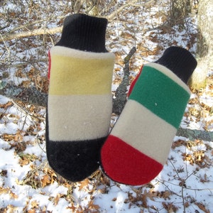 May include: A pair of colorful mittens with a black cuff and a striped design. One mitten features yellow, cream, and red stripes, while the other has green, cream, and red stripes. The mittens are made of a thick, warm material.