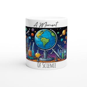Peut inclure: Une tasse en céramique blanche avec une illustration colorée d'un globe terrestre, des béchers et une lunette astronomique. Le texte "A Moment of Science" est imprimé sur la tasse.