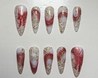 May include: Set of ten false nails with a white base and gold and red dragon designs.